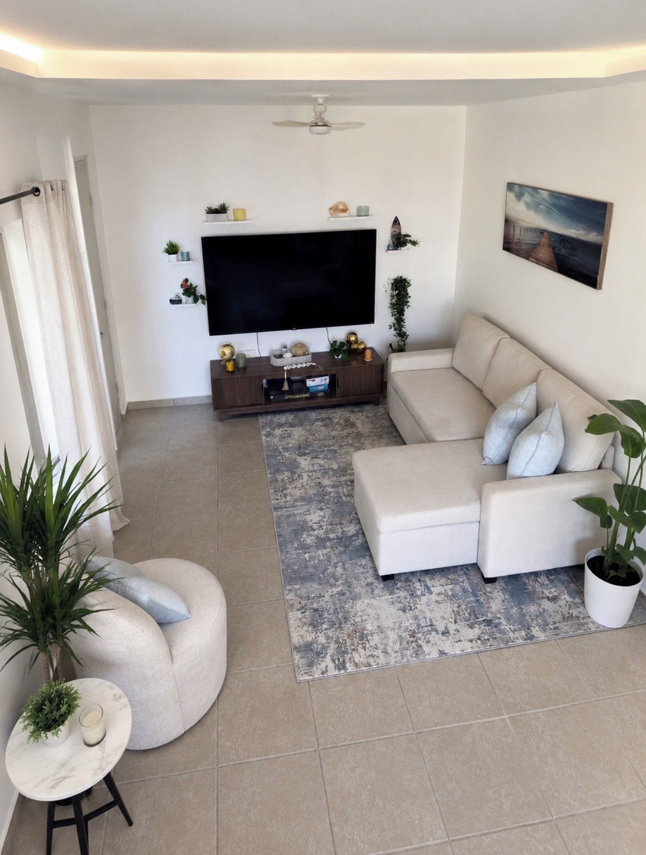 Una sala moderna con un sofá modular, un televisor de pantalla plana, un ventilador de techo y un cuadro en la pared.