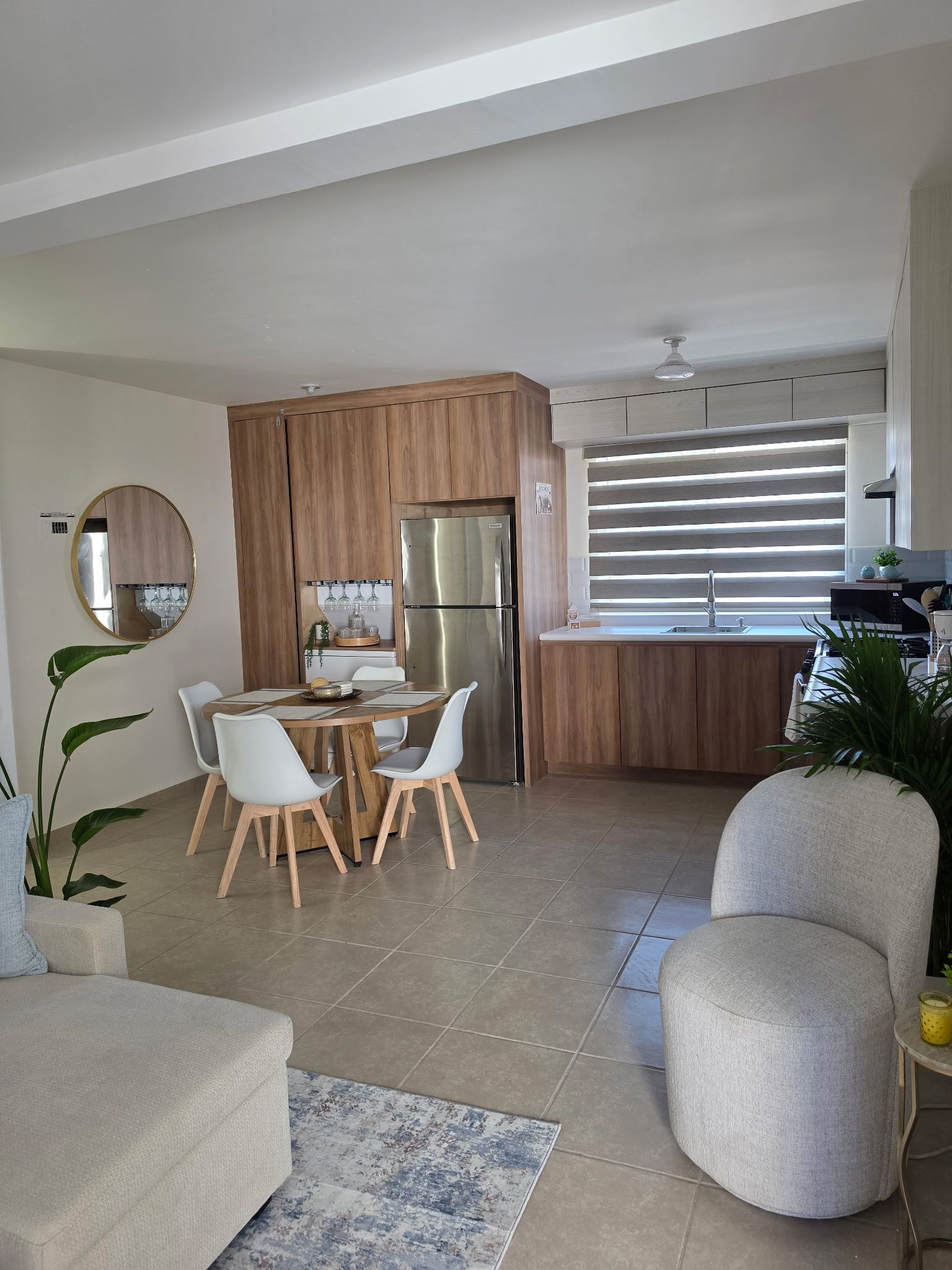 Una cocina moderna con refrigerador empotrado, armarios de madera y un comedor con mesa redonda y sillas.