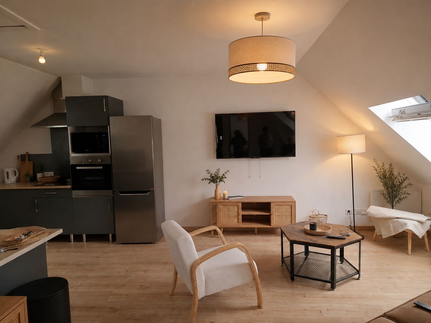 Eine moderne Küche mit Einbauofen und Mikrowelle, ein großer Flachbildfernseher an der Wand und ein Essbereich mit Holztisch und Stühlen.