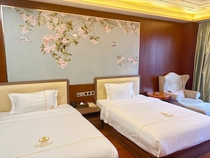 A hotel room with two beds, a sitting area with a chair, a decorative wall, and a small table. - Haizhigang Hotel (Sihanoukville)