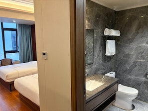 A hotel room with a bed, a bathroom with a marble sink and a toilet, and a window with curtains. - Haizhigang Hotel (Sihanoukville)