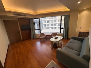A spacious living area with a sofa, a round table, and two chairs. - Haizhigang Hotel (Sihanoukville)
