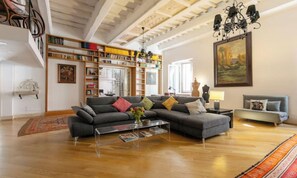 A spacious living room with a sectional sofa, a coffee table, and a bookshelf filled with books. - TIMELESS ROME APARTMENT WITH PARQUET FLOORS AND A FULLY EQUIPPED KITCHEN (Roma)