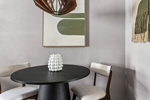 En matplats med ett runt bord, två stolar, en vas och en hängande lampa.