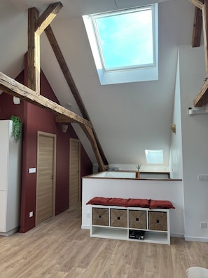 A loft bedroom with a skylight, wooden beams, a white wardrobe, and a built-in bench with storage. - New Listing (Sains-du-Nord)