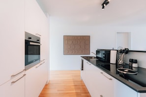 Een moderne keuken met witte kasten, een zwart aanrecht en een houten vloer.