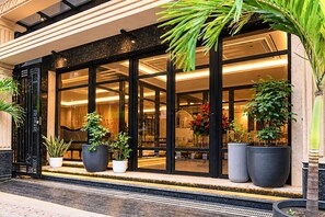 L’entrée d’un hôtel, avec de grandes portes vitrées, des plantes en pot et un intérieur bien éclairé.