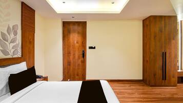 A bedroom with a bed, a wooden wardrobe, a nightstand with a phone, and a ceiling light.