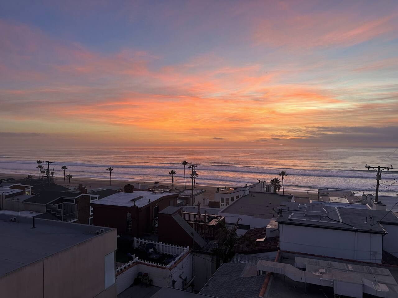 A coastal residential area with buildings and a beach in the background.