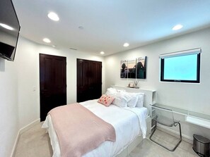 Un dormitorio con cama, televisión instalada en la pared y ventana.