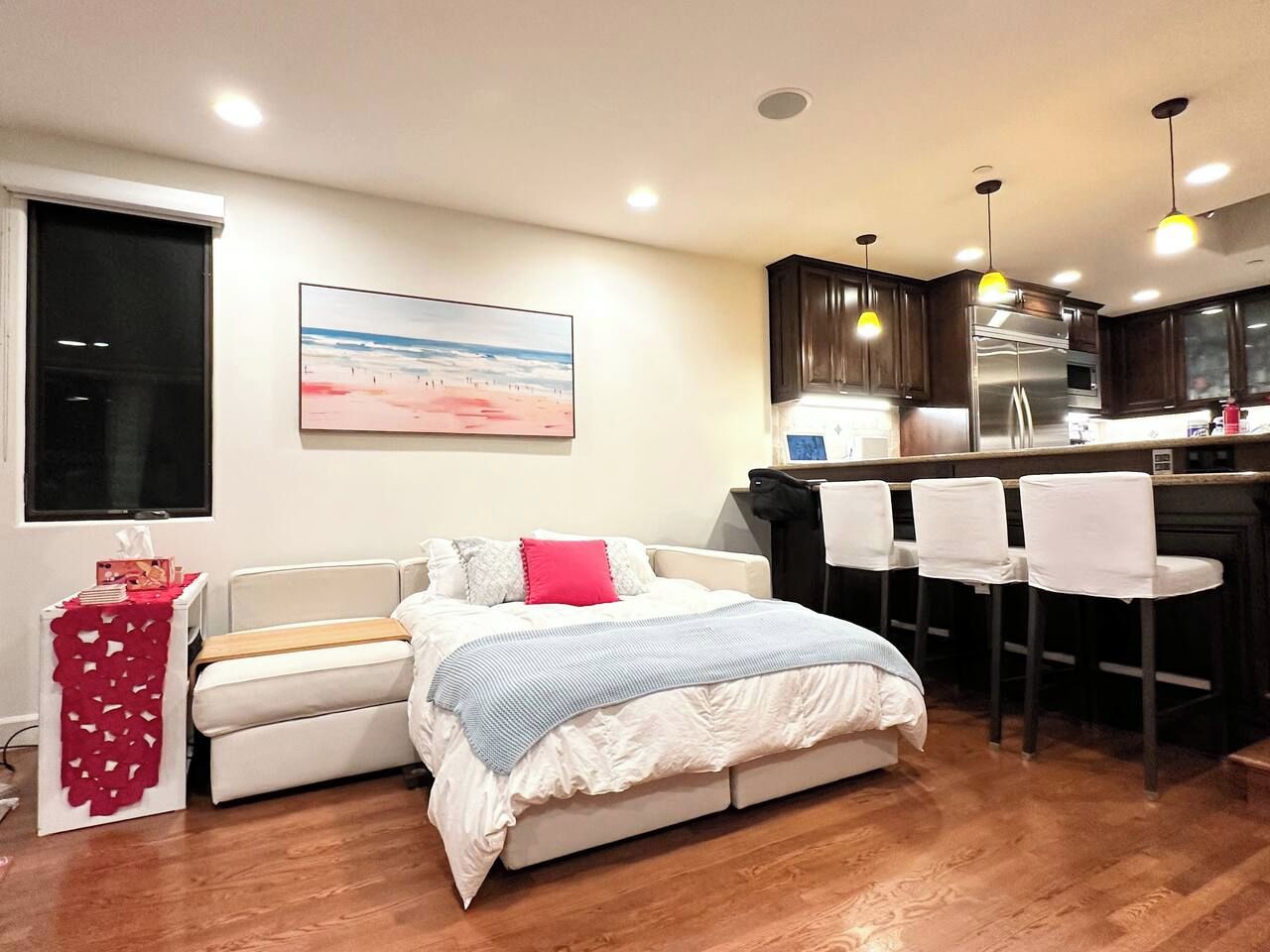 A bedroom with a bed, bedside table, and a window.