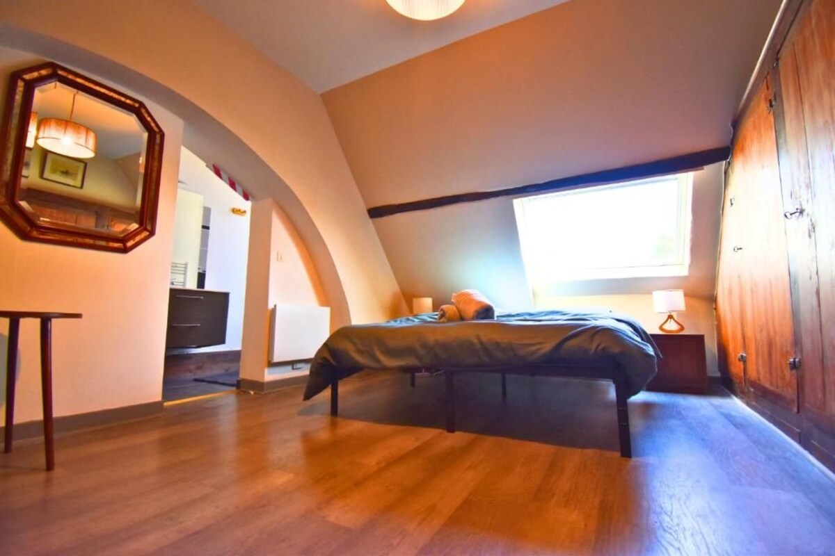 Ein Schlafzimmer mit einem Bett, einem Holzschrank, einem Spiegel und einem Fenster.