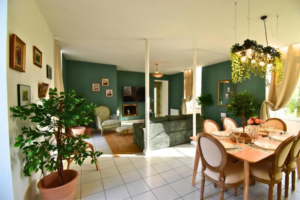 A dining area with a table set for six, a green sofa, and a potted plant.