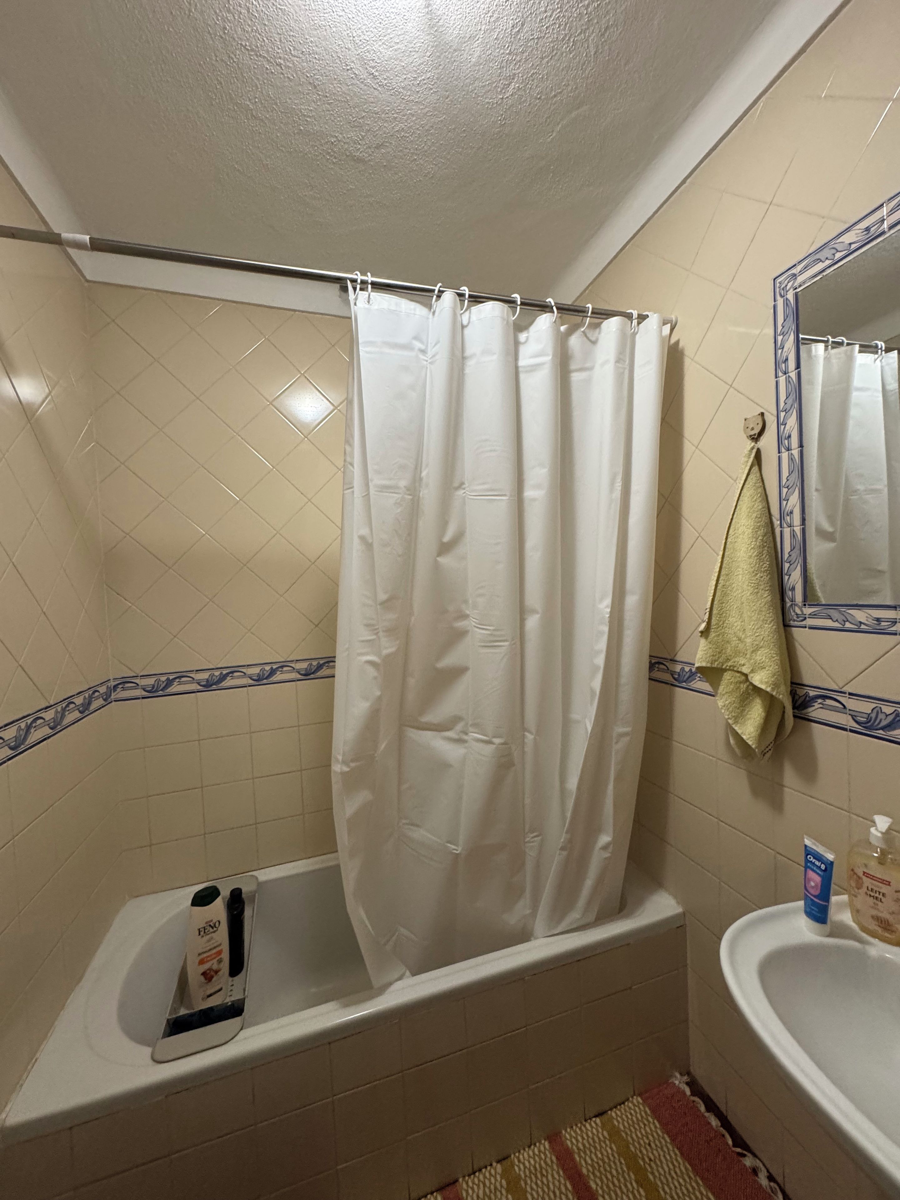 Un baño con bañera, cortina de ducha, toalla y espejo.
