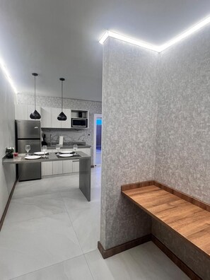Een moderne keuken met een vast eiland, roestvrijstalen apparatuur en hanglampen.