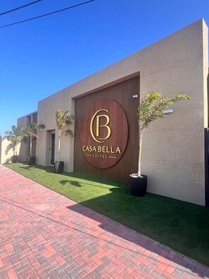 Een modern gebouw met een groot bord waarop 'CASABELLA SUITES' staat en een verharde looppad.