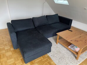 A black sectional sofa with a wooden coffee table and a magazine. - New Listing (Kürten)