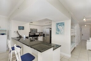 Una cocina moderna con armarios blancos, una isla central con asientos y un refrigerador.