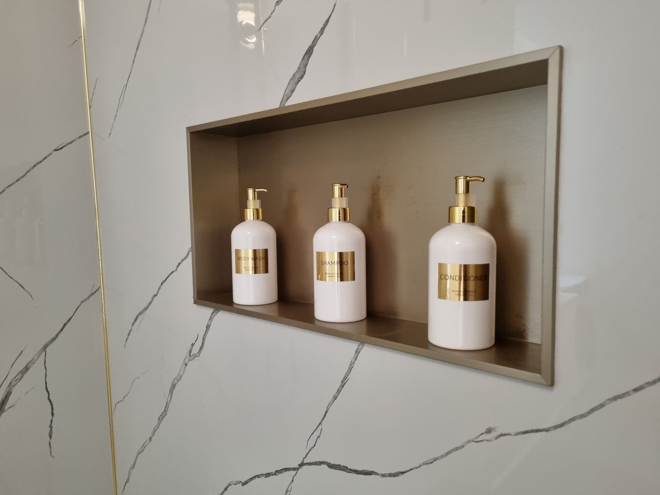 Ein Badezimmerschrank mit drei weißen Flaschen für Toilettenartikel.