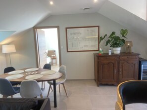 Een eetgedeelte met een ronde tafel, stoelen, een kast en een plant.