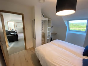 Une chambre à coucher avec un lit, une fenêtre donnant sur un beau paysage, une armoire intégrée et un miroir.
