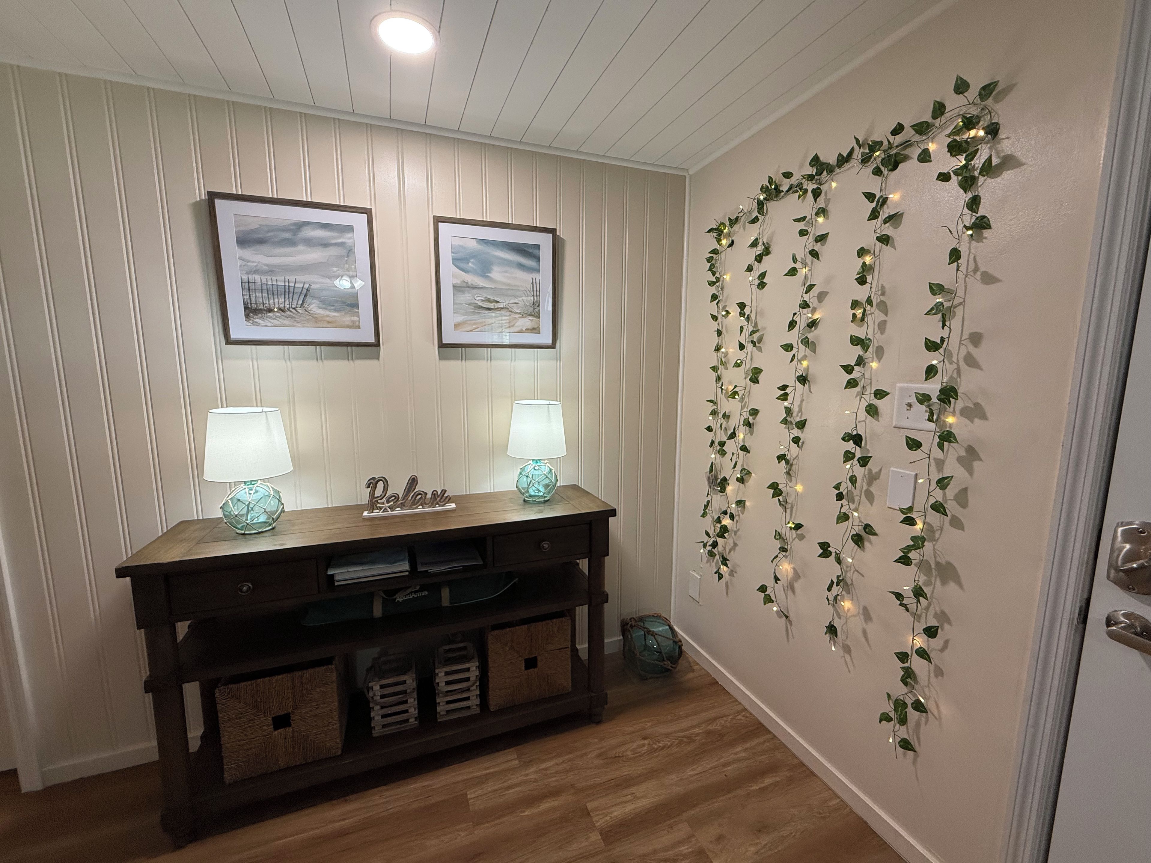A room with a wooden console table, two wall-mounted lamps, and a decorative garland with lights.