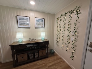 A room with a wooden console table, two wall-mounted lamps, and a decorative garland with lights. - Spacious 4-bedroom house in Homosassa, huge parking! Family and pets friendly (Homosassa)