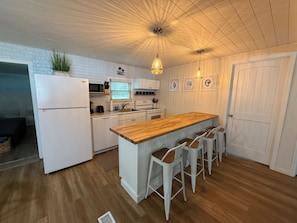 A kitchen with a wooden island, white cabinetry, and bar stools. - Spacious 4-bedroom house in Homosassa, huge parking! Family and pets friendly (Homosassa)