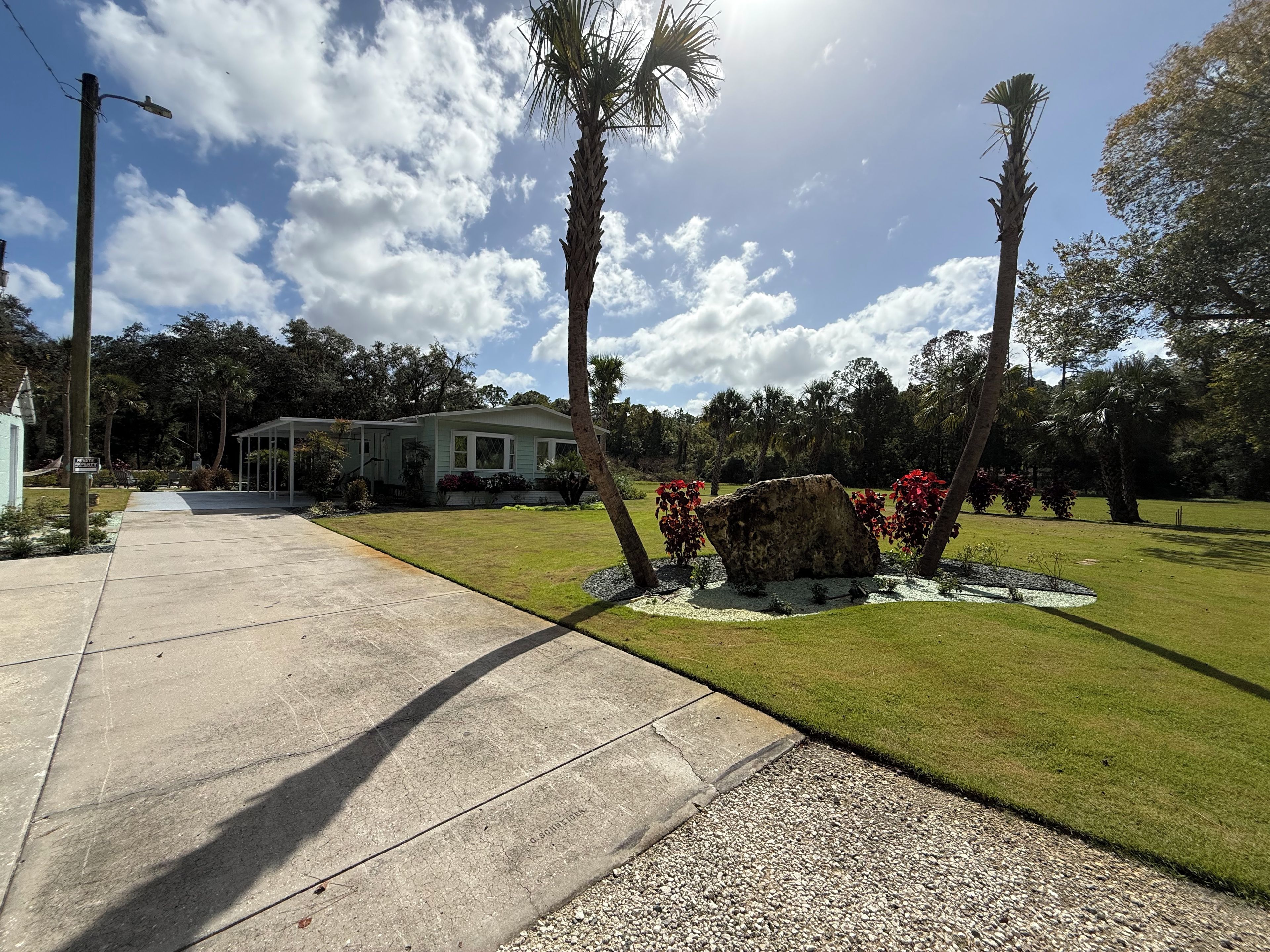 A residential property with a paved driveway, a lawn, and a house with a porch.