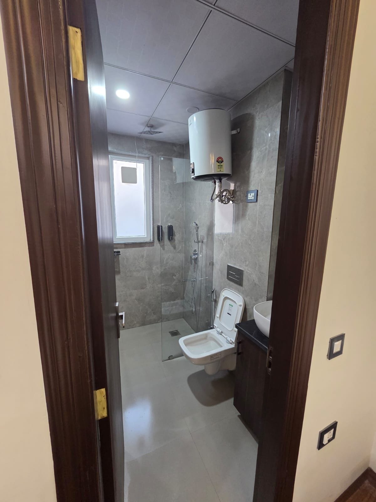 Une salle de bain moderne dotée d’une douche à parois de verre, de toilettes et d’un lavabo intégré.