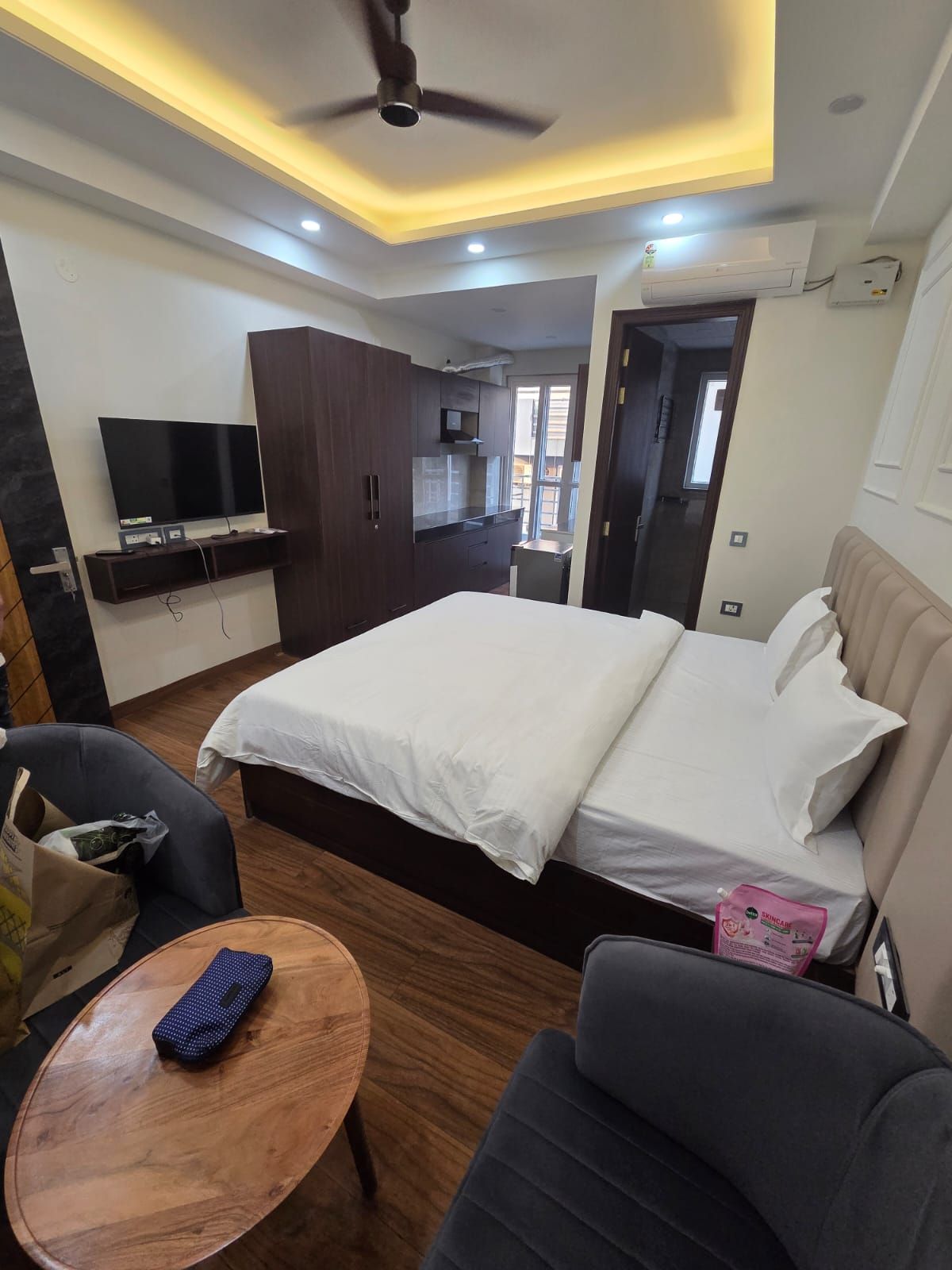 Una habitación de hotel con una cama, televisor, escritorio y ventilador de techo.