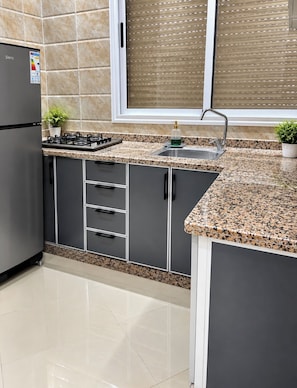 A kitchen with a gas stove, sink, and cabinets.