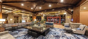 Eine geräumige Lobby mit Steinwand, einer Rezeption und einer Sitzecke mit Sofas und einem Couchtisch.