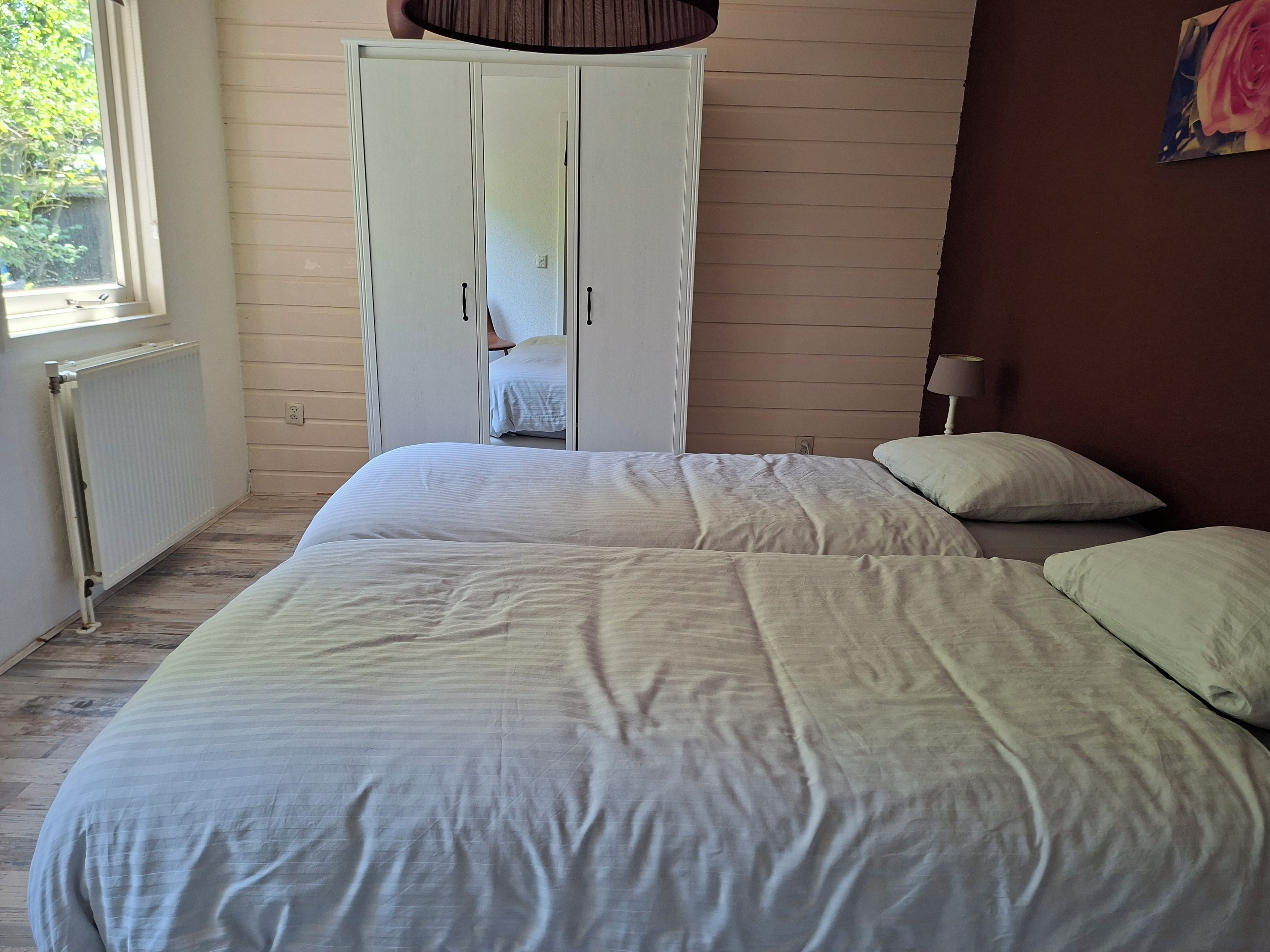 Un dormitorio con cama, armario y ventana.