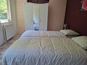 Un dormitorio con cama, armario y ventana.