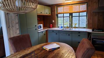 Una cocina con armarios de madera, microondas, lavamanos y una mesa de comedor con sillas.