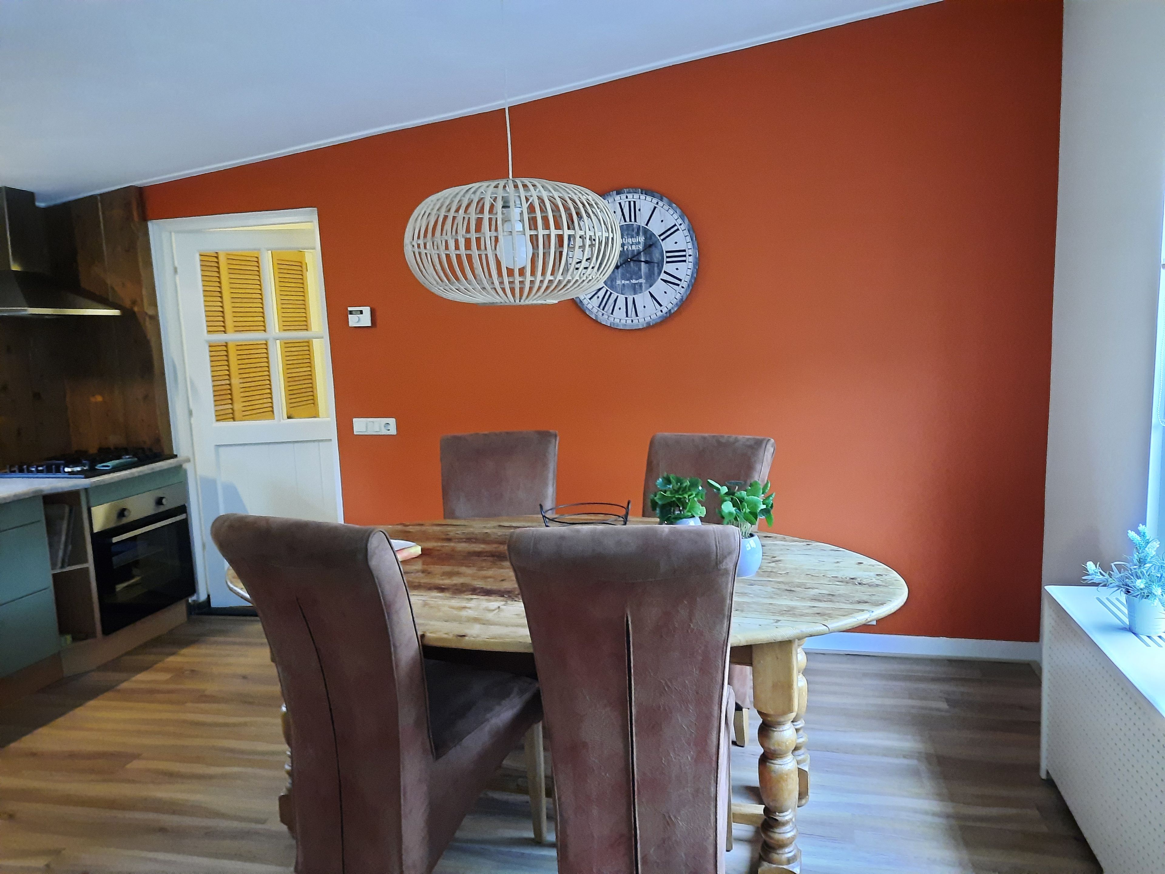 Un comedor con una mesa redonda, sillas y un reloj de pared.