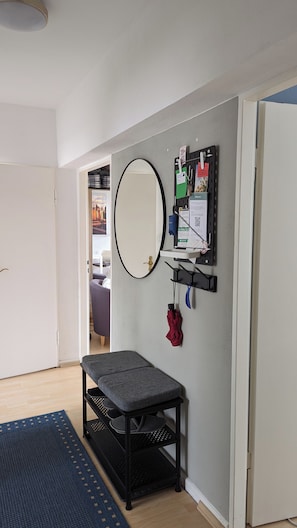 Een gang met een bankje, een spiegel aan de muur en een prikbord met diverse spullen.