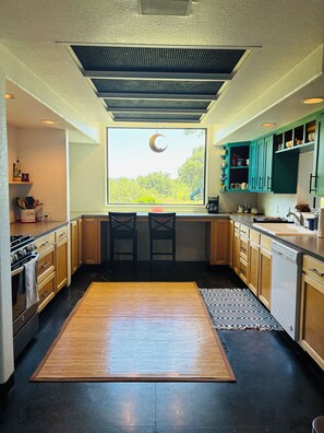 Una cocina moderna con un amplio ventanal, una decoración con forma de luna creciente y piso de madera.