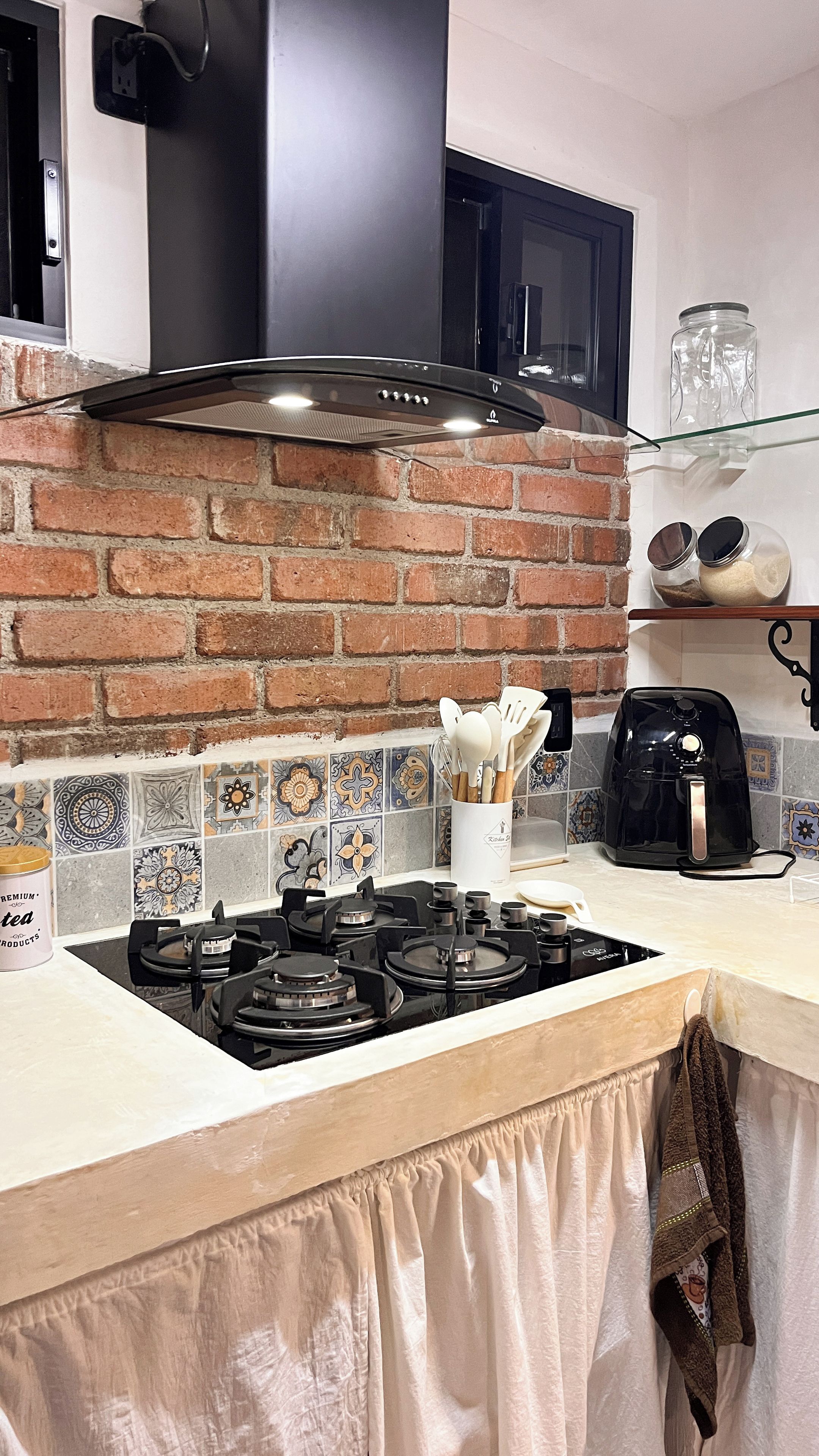 Une cuisine équipée d’une cuisinière à gaz, d’une hotte noire, d’un four à micro-ondes et d’une machine à café.