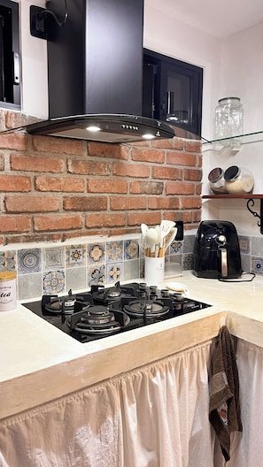 Une cuisine équipée d’une cuisinière à gaz, d’une hotte noire, d’un four à micro-ondes et d’une machine à café.