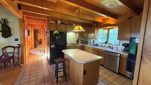 Un interior de madera con isla de cocina, armarios de madera y una lámpara colgante.