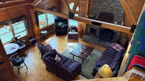 Interior de una cabaña con chimenea, muebles de madera y pared de piedra.