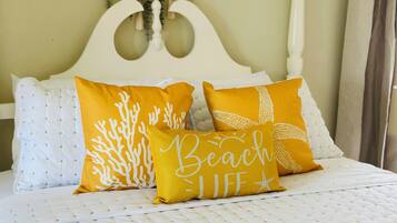A bed with white bedding and two yellow pillows with text.