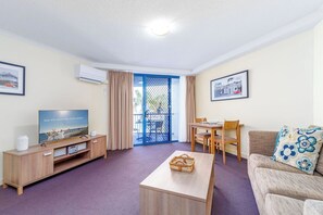 A furnished living room with a television, a dining table, and a sofa. - Mantra Apt - 2nd Floor + Views (Urangan)