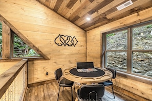A wooden interior with a round table, chairs, and a window with a view of a rocky landscape. - Indoor Pool • Arcade • Hot Tub  Pigeon Forge (Pigeon Forge)