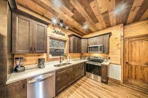 A kitchen with wooden paneling, stainless steel appliances, and a sign that reads 'Kitchen'. - Indoor Pool • Arcade • Hot Tub  Pigeon Forge (Pigeon Forge)