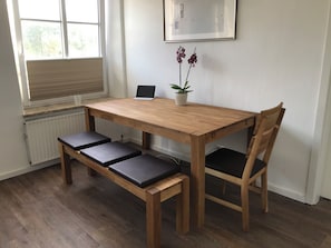 A wooden dining table with a laptop and a potted plant on it. - New Listing (Altenkrempe)