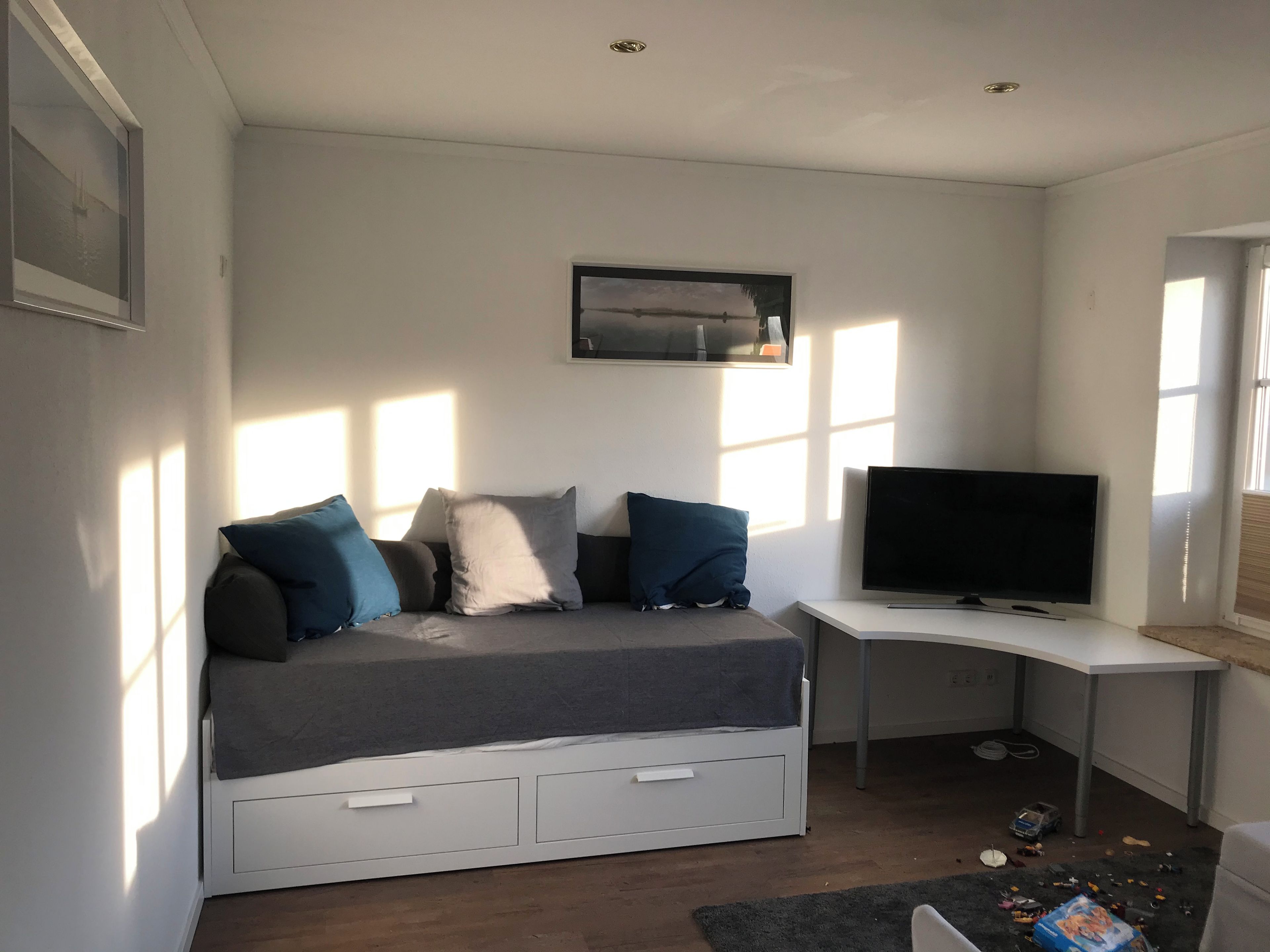 A bedroom with a bed, a desk, a television, and a window.