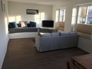 A modern living room with a sofa, a television, and a dining area. - New Listing (Altenkrempe)